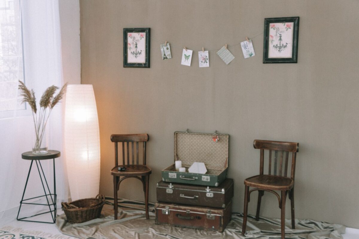 Cozy vintage room with wooden chairs, stacked luggage, and decorative wall art.